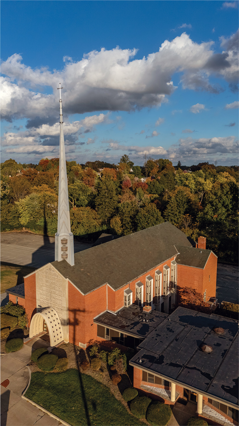 The outside of mt lebanon lutheran church. the red brick building has a massive peak sticking out of the front of the building with a cross at the top.