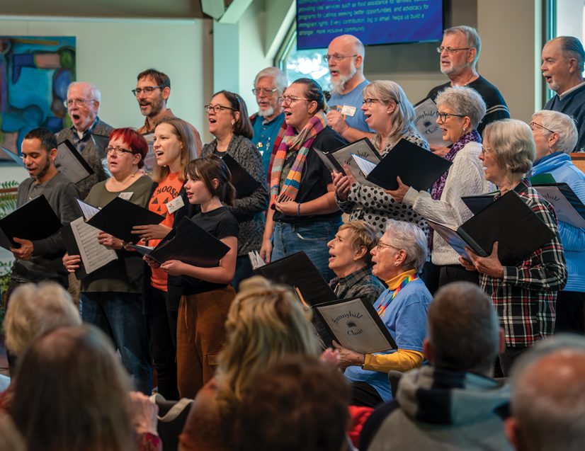 a choir of a diverse set of people singing during a church service, people are watching and singing in the foreground