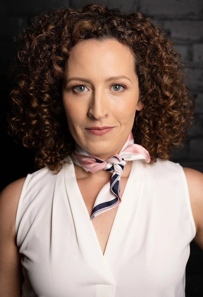 headshot of woman with curly brown hair with tank top and pink multicolored scarf