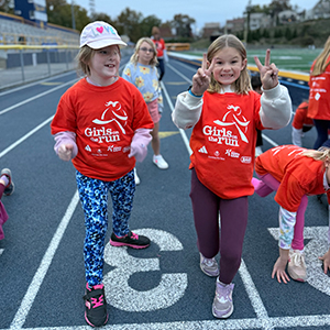 children in red shirts running on a track outdoors