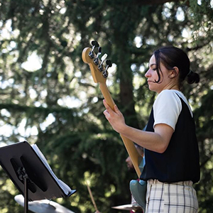 girl with short dark hair playing bass outside
