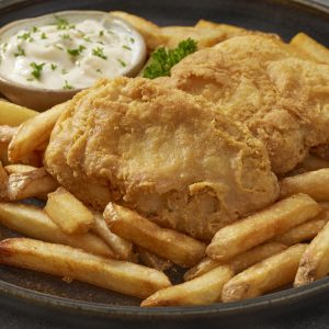 Beer battered fish served with french fries, tartar sauce, and lemon