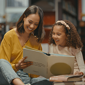 woman and girl reading a book on the floor in a library
