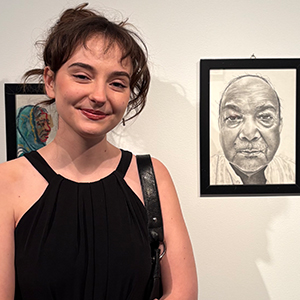 young woman smiling in front of artwork in an exhibit