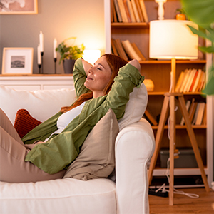 woman laying on couch with arms above her head smiling