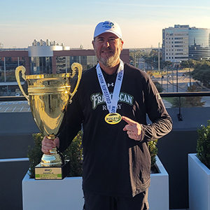 man holding trophy and pointing to medal around neck