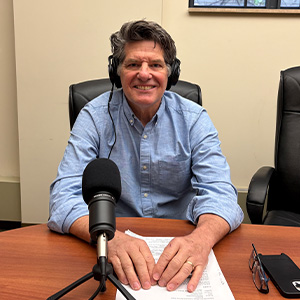 Man sitting behind microphone wearing headphones
