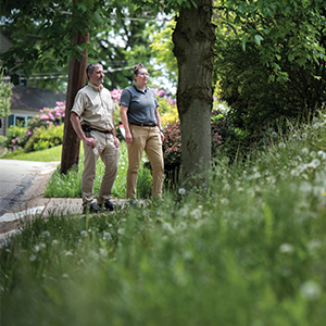 two people looking at a yard on a suburban street