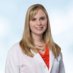 woman with white doctors coat and orange shirt
