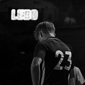 black and white photo of soccer player from behind with LEBO lights in background