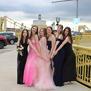 group photo of teenage girls in prom gowns with downtown Pittsburgh bridges in background