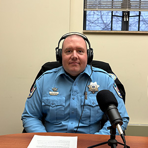 man wearing headphones and a paramedic uniform, sitting in front of a microphone.